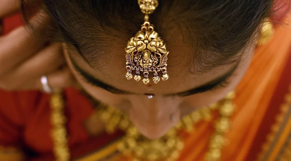 هندية ترتدي قطعة من الحُلي الذهبية داخل متجر مجوهرات في بنغالور (إ.ب.أ)