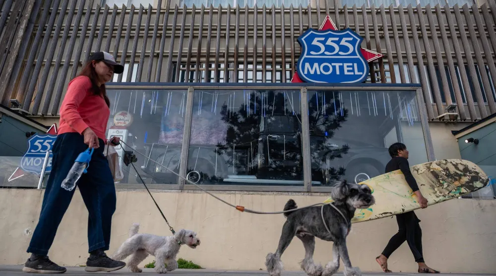 سيدة تسير مع كلابها أمام فندق في مدينة فوجيساوا اليابانية (أ.ف.ب)