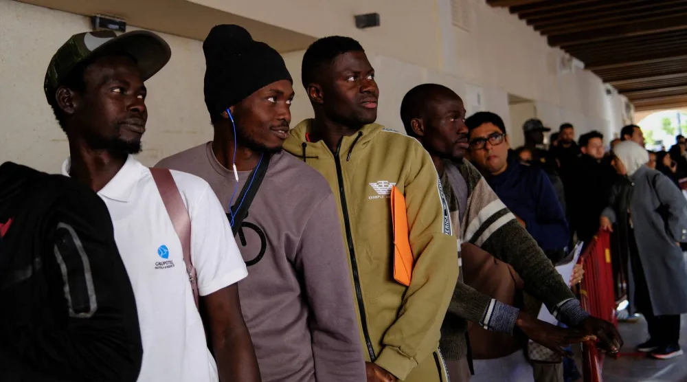 أشخاص يصطفون في طوابير للحصول على شهادة وضع قانوني لتسوية أوضاعهم القانونية المتعلقة بالهجرة في مبنى بلدية ألميريا بجنوب إسبانيا 20 أبريل 2026 (رويترز) 