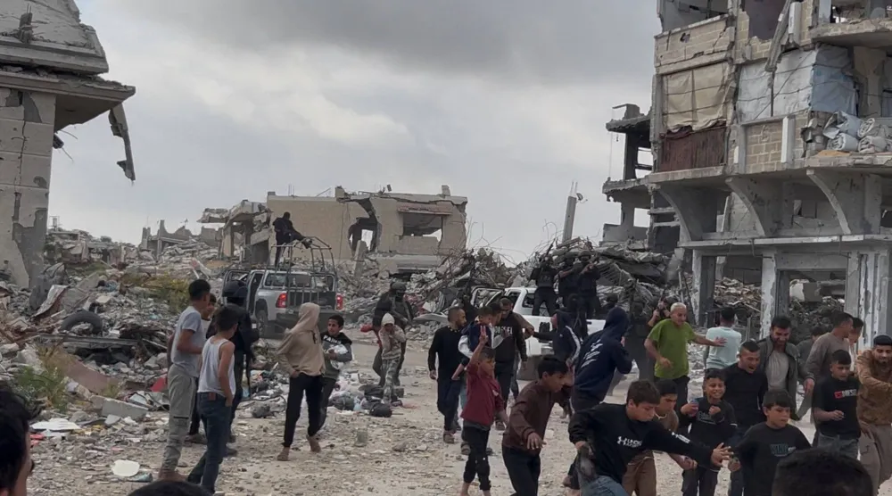 فلسطينيون إلى جانب مقاتلين من فصائل غزة عقب اشتباكات مع ميليشيات مدعومة من إسرائيل في خان يونس جنوب القطاع يوم الاثنين (صورة من فيديو بثته رويترز)