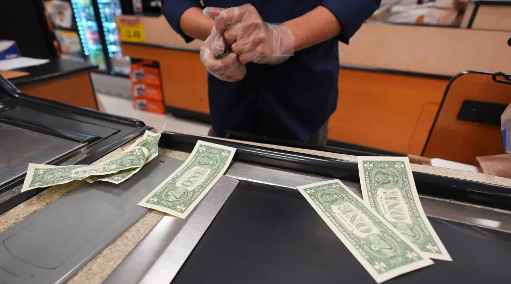 أمين صندوق في متجر بقالة يسحب أوراقاً نقدية من فئة الدولار (أ.ب)