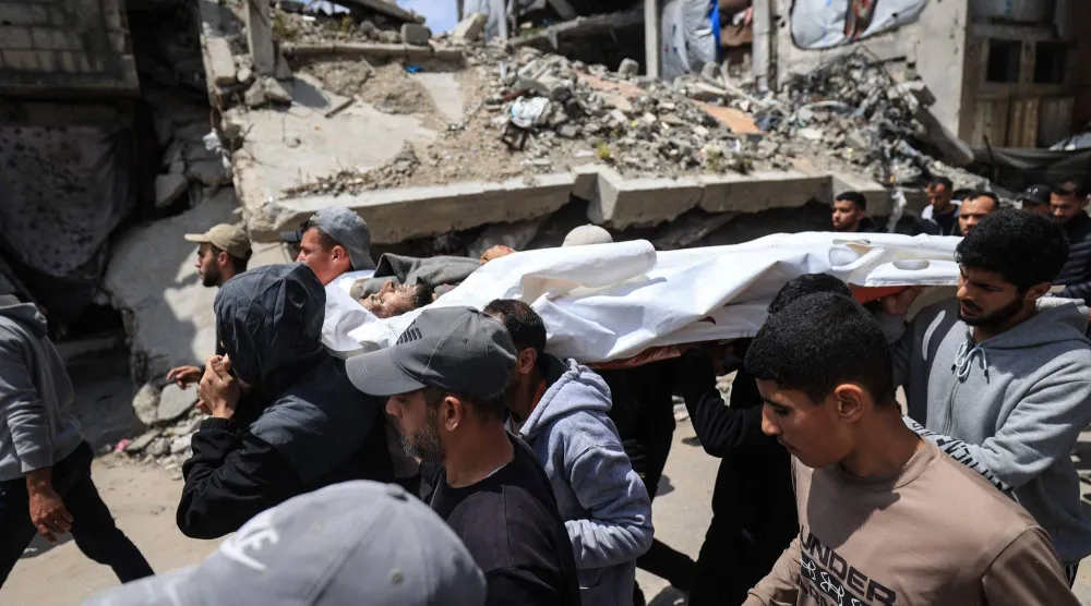 فلسطينيون نازحون يحملون جثمان أيمن أبو حسنة خلال جنازته في مخيم البريج للاجئين وسط قطاع غزة أمس والذي أفادت التقارير بمقتله ليلاً في غارة إسرائيلية أثناء قيادته دراجة نارية (أ.ف.ب)