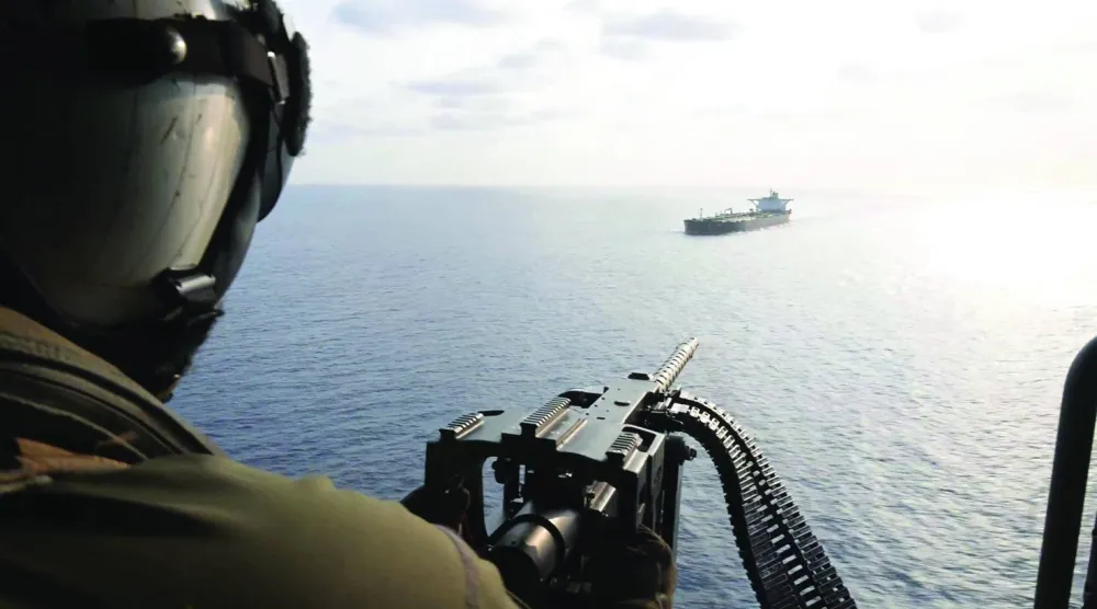 لقطة من فيديو لجندي أميركي على متن مروحية وهو يوجه تحذيراً إلى سفينة إيرانية قرب مضيق هرمز أمس (سنتكوم)