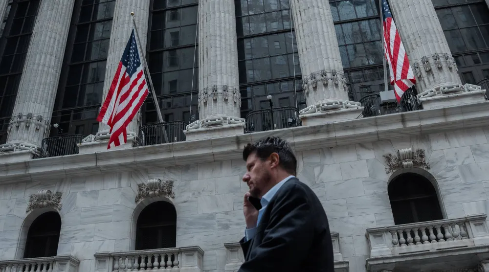 شخص يتحدث هاتفياً في أثناء مروره قرب مبنى بورصة نيويورك (إ.ب.أ)