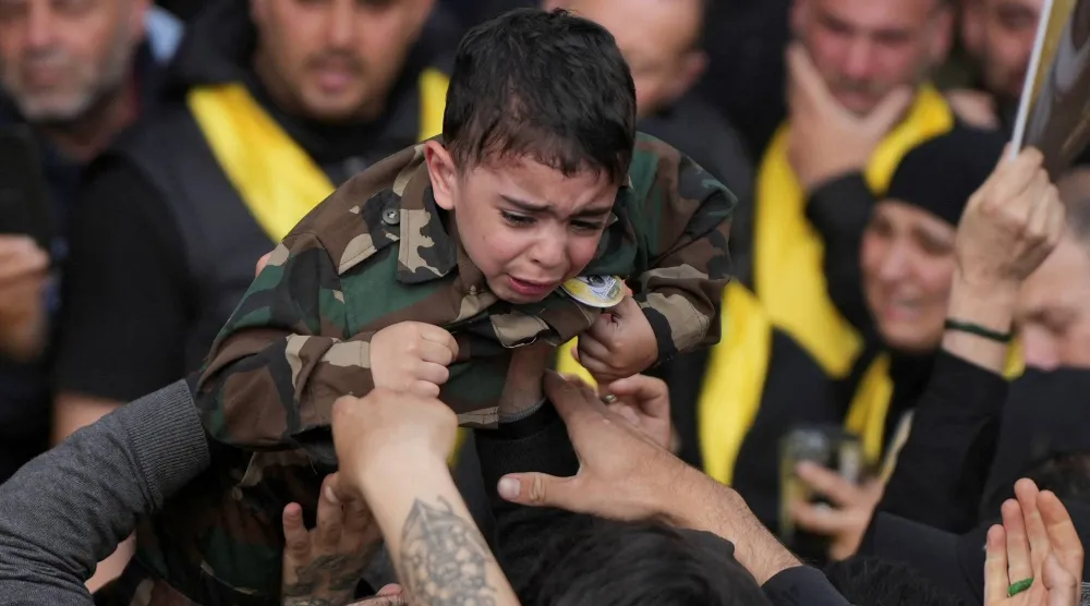 طفل يرتدي البزة العسكرية خلال تشييع مقاتل من «حزب الله» بالضاحية الجنوبية لبيروت في أثناء فترة الهدنة مع إسرائيل (رويترز)