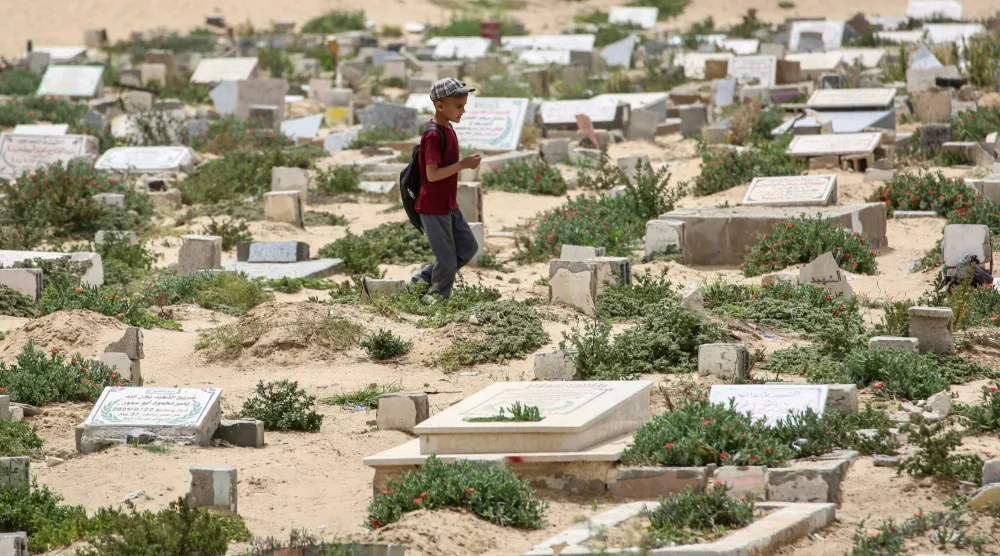 طفل يسير في مقبرة خان يونس جنوب قطاع غزة (أ.ف.ب)