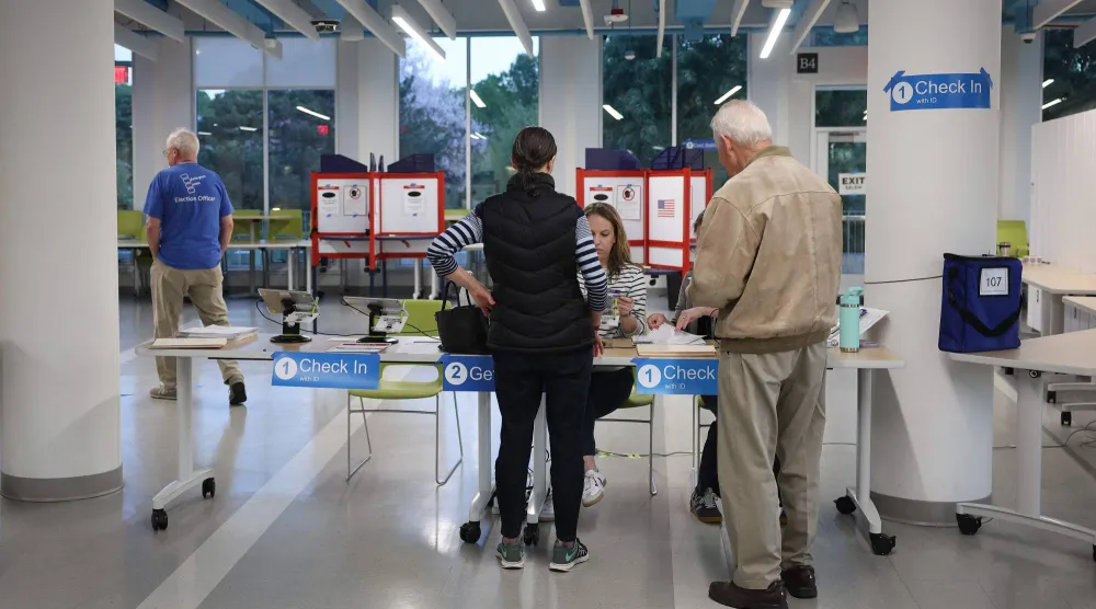 ناخبون يسجلون أسماءهم لدى موظفي الاقتراع قبل الإدلاء بأصواتهم في مركز اقتراع في أرلينغتون - فيرجينيا (أ.ف.ب)