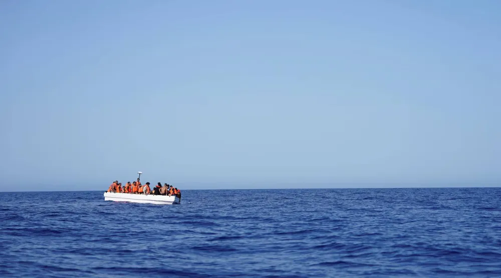 مهاجرون على متن قارب ينتظرون المساعدة من قارب إنقاذ في البحر المتوسط 24 يوليو 2025 (رويترز)