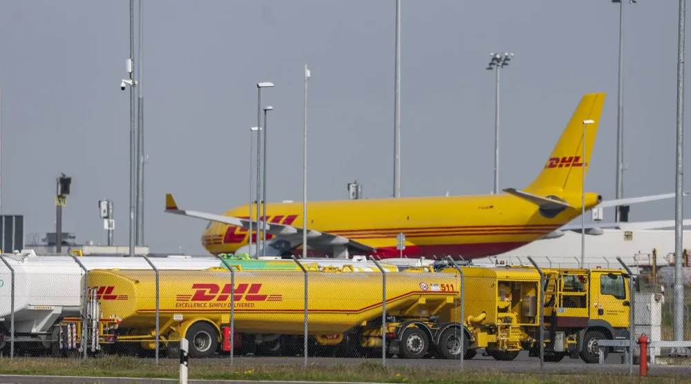 طائرة تابعة لشركة «دي إتش إل» تقف خلف عدة شاحنات صهريجية في مركز الشركة بمطار لايبزيغ (د.ب.أ)