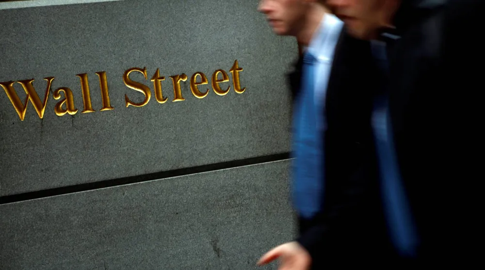 أشخاص يمرون أمام بورصة نيويورك في وول ستريت (رويترز)
