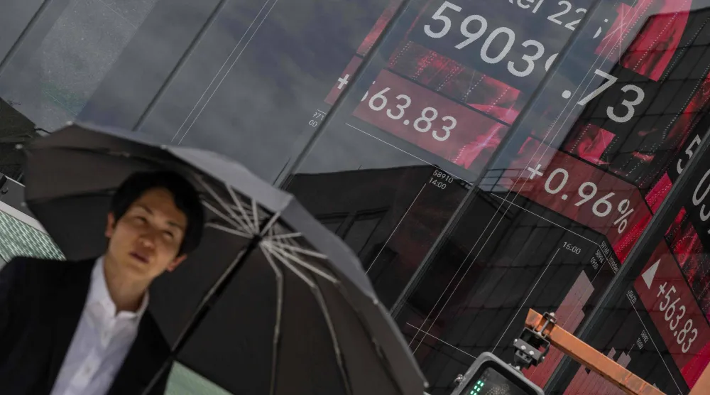 رجل يمر أمام شاشة تعرض حركة الأسهم بالعاصمة اليابانية طوكيو (أ.ف.ب)