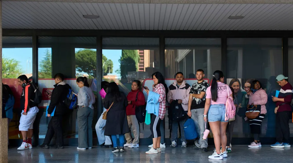 يصطف المهاجرون في طوابير للحصول على شهادة النقل العام التي ستسمح لهم بطلب الحصول على تصاريح عمل وإقامة سريعة بالعاصمة الإسبانية مدريد (أ.ب)