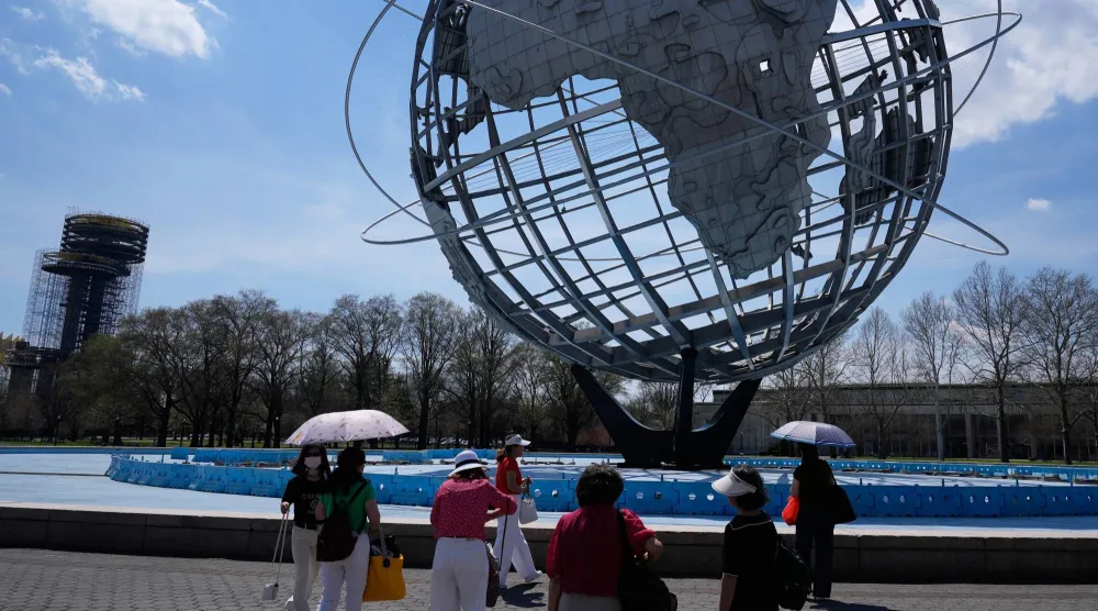 أشخاص يحملون مظلاتٍ احتماءً من الشمس في نيويورك (أ.ب)