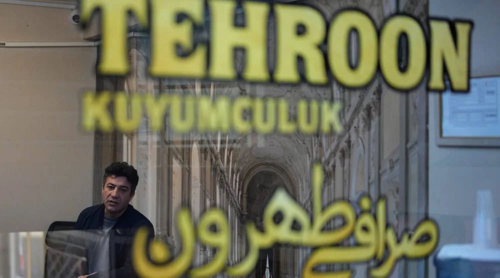 إيراني يتحدث إلى أحد الزبائن داخل محل صرافة يملكه في إسطنبول (أ.ب)