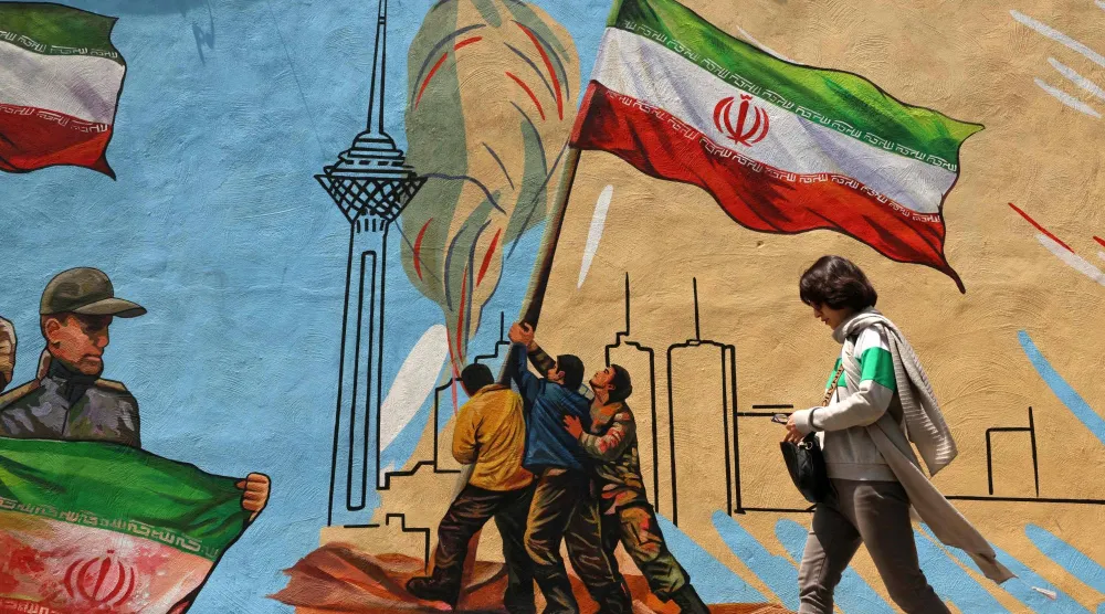 امرأة إيرانية تمر بجوار جدارية مناهضة للولايات المتحدة وإسرائيل في طهران وسط تمديد لهدنة وقف إطلاق النار بالمنطقة (أ.ف.ب)