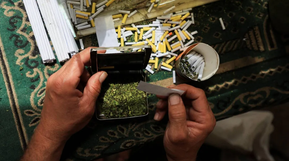 بائع فلسطيني يبيع سجائر مصنوعة من أوراق الملوخية المجففة كبديل للتبغ (رويترز)