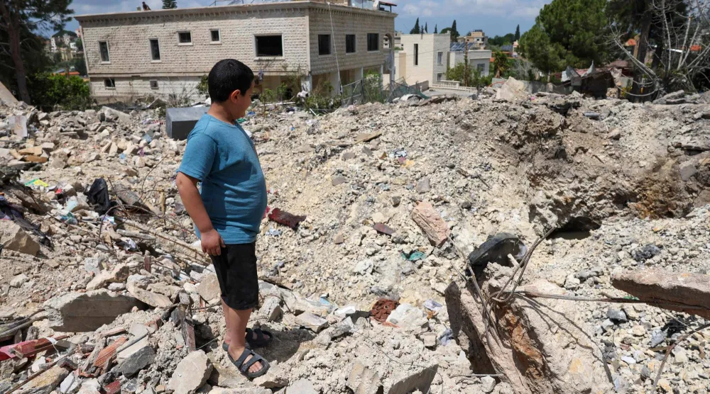 طفل يقف على حطام مبنى دمرته غارة إسرائيلية في بلدة كفرصير بجنوب لبنان (أ.ف.ب) 