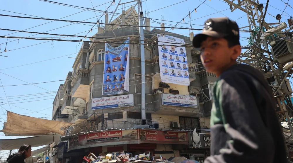 صبي فلسطيني يمر قرب لافتات لمرشحي الانتخابات المحلية في دير البلح بوسط غزة الثلاثاء (أ.ف.ب)