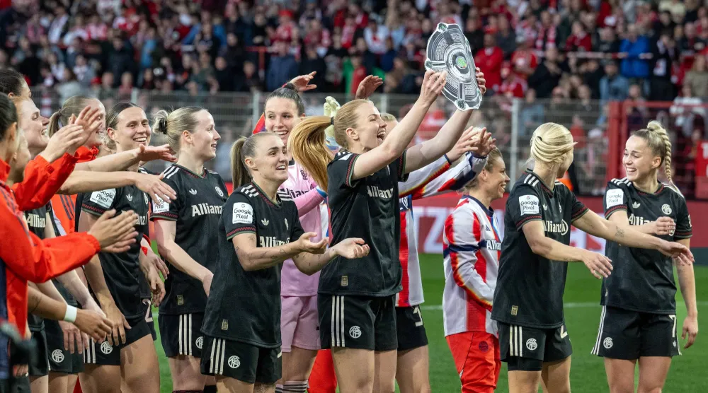 تحتفل لاعبات بايرن ميونيخ بالفوز وهن يحملن نسخة من درع البطولة عقب صافرة النهاية (د.ب.أ)