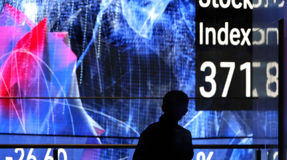 رجل يقف أمام لوحة مؤشرات سوق الأسهم في طوكيو (إ.ب.أ)