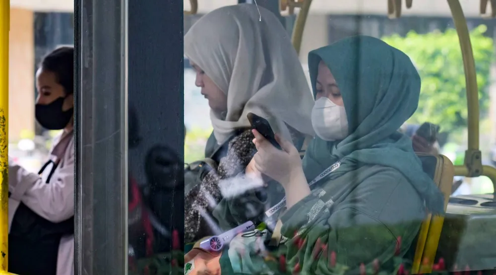 ركاب ينشغلون بهواتفهم الذكية في حافلة عامة في جاكرتا (أ.ف.ب)