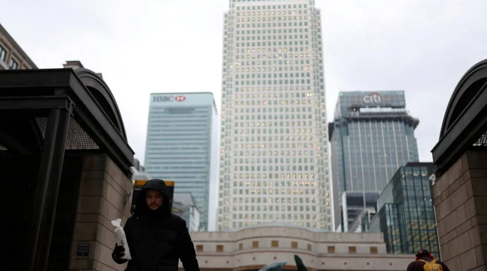 عمال يسيرون عبر ساحة كابوت في منطقة كاناري وارف المالية (لندن)