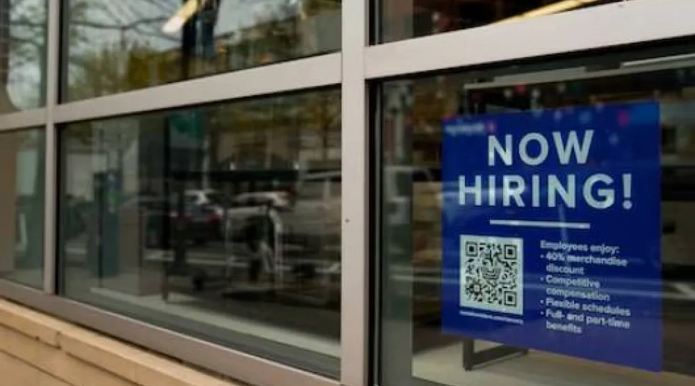 تظهر لافتة لتوظيف الموظفين تتضمن رمز استجابة سريعة في نافذة أحد المتاجر في أرلينغتون - فرجينيا (رويترز)