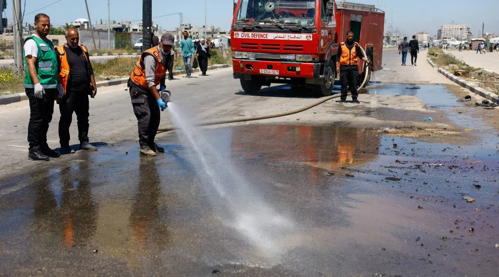 أفراد من الدفاع المدني يزيلون آثار غارة إسرائيلية في وسط قطاع غزة (رويترز)