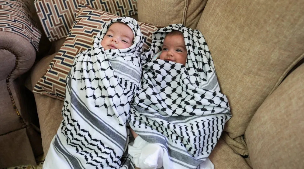 ابنتا الشاب الفلسطيني عودة عواودة (25 عاماً) الذي قُتل في هجوم استيطاني إسرائيلي خلال جنازته قرب رام الله في الضفة الغربية الخميس (رويترز)