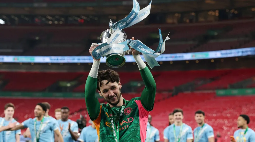 حارس مرمى مان سيتي جيمس ترافورد يحمل كأس الرابطة الإنجليزية (رويترز)