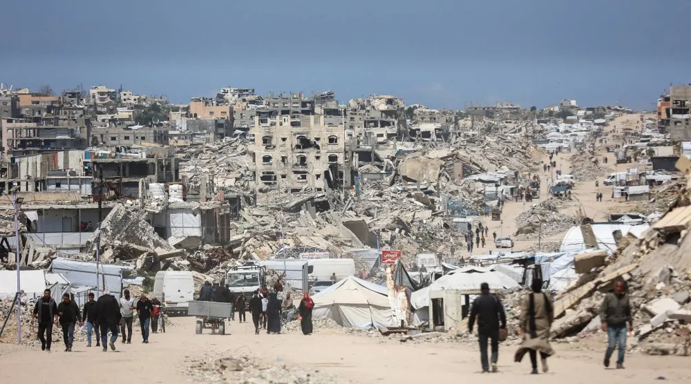 فلسطينيون يسيرون وسط أنقاض المباني المدمرة في مخيم جباليا للاجئين شمال قطاع غزة (أ.ف.ب)