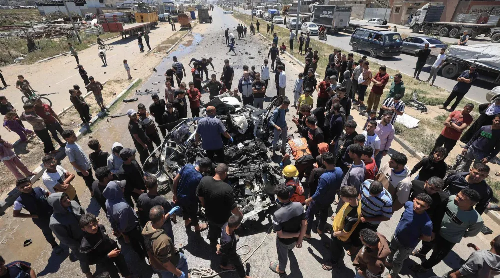 فلسطينيون يتجمَّعون حول سيارة مُدمَّرة بعد استهدافها بغارة إسرائيلية في شارع صلاح الدين جنوب مخيم البريج بقطاع غزة (أ.ف.ب)