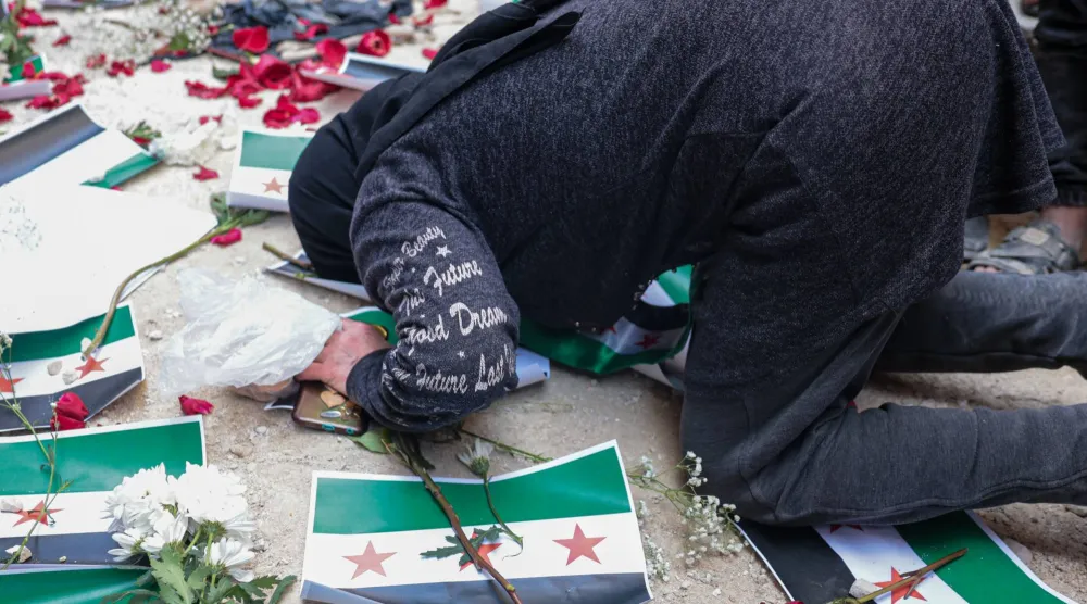 سورية تقبل الأرض خلال الاحتفال بالقبض على المتهم بارتكاب «مجزرة التضامن» في حي التضامن بدمشق الجمعة (إ.ب.أ)