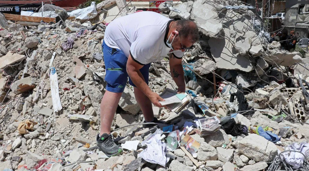 محمّد علي حجازي يبحث عن تذكارات من عائلته التي قُتل 5 أفراد منها بغارة إسرائيلية في مدينة صور (أ.ف.ب)