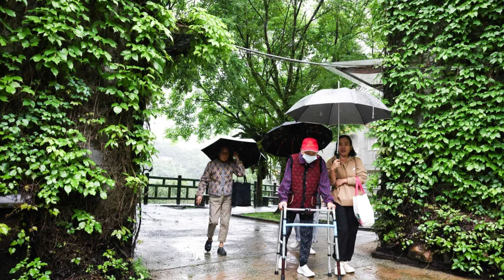 أشخاص كبار في السن يتنزهون تحت المطر في مدينة تايبيه الجديدة (أ.ف.ب)