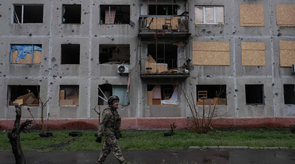 جندي أوكراني وهو يمر بجوار مبنى متضرر في ضواحي دروجكيفكا بمنطقة دونيتسك (أ.ف.ب)