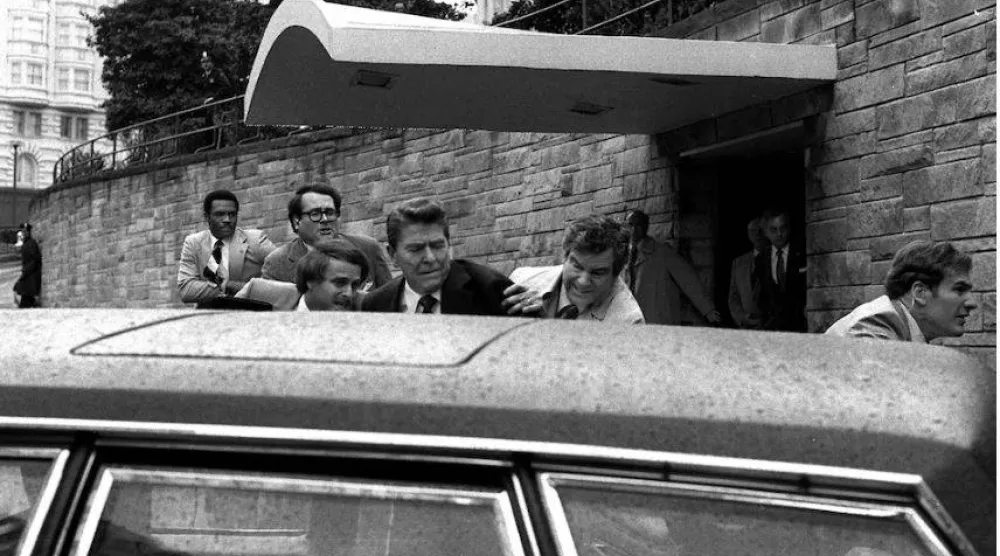رونالد ريغان يُدفَع إلى سيارة من قبل الأمن بعد محاولة اغتياله عام 1981 (أ.ب)