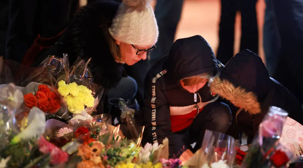 سويسريون يشعلون الشموع أمام حانة في منتجع تزلج سويسري اشتعلت بها النيران ليلة رأس السنة (رويترز)