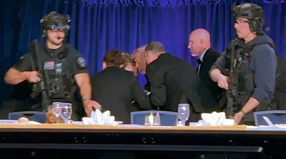 لحظة إخراج الرئيس الأميركي دونالد ترمب إلى خارج قاعة حفل عشاء جمعية مراسلي البيت الأبيض (رويترز)