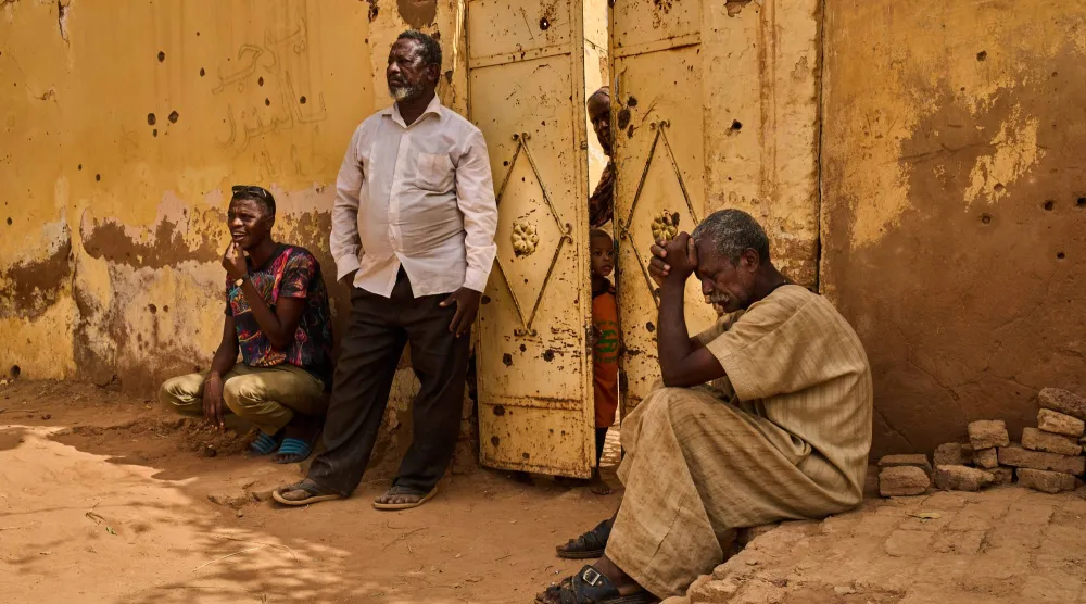 سودانيون ينتظرون استخراج رفات شقيقهم الذي قتلته «قوات الدعم السريع» في أم درمان (أ.ب) 