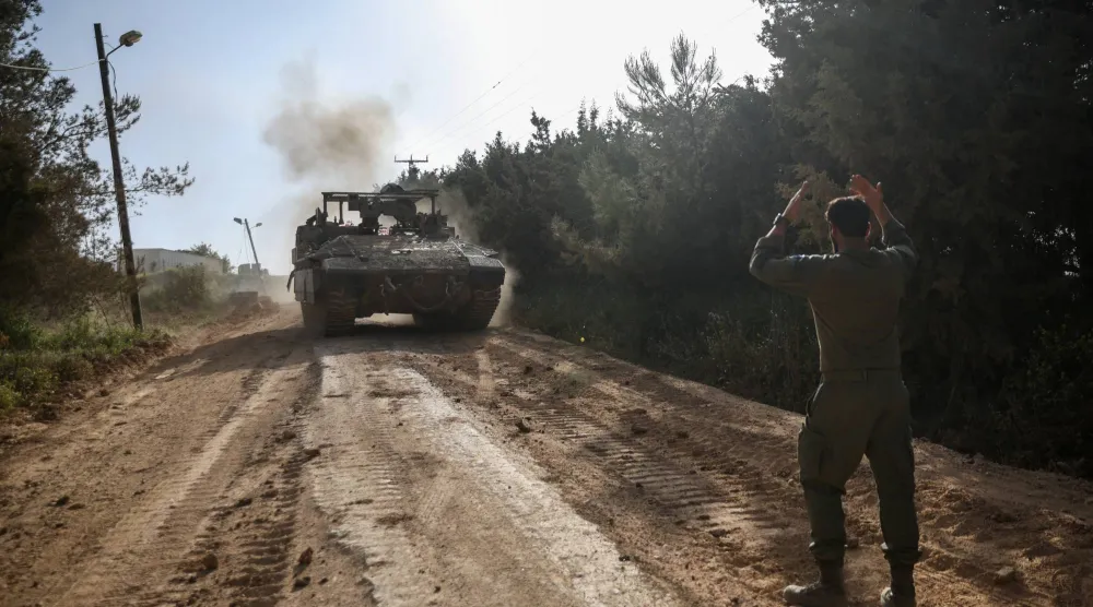 جندي إسرائيلي يوجه دبابة على الضفة الإسرائيلية من الحدود مع لبنان (رويترز)