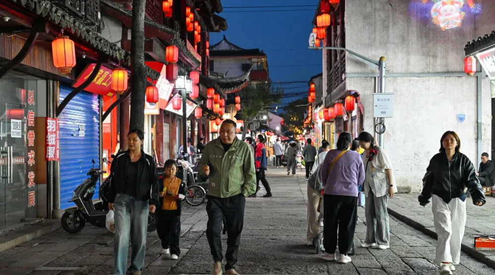 يسير الناس على طول أحد الشوارع أثناء زيارتهم لمدينة فنغانغ القديمة على مشارف شنغهاي (أ.ف.ب)