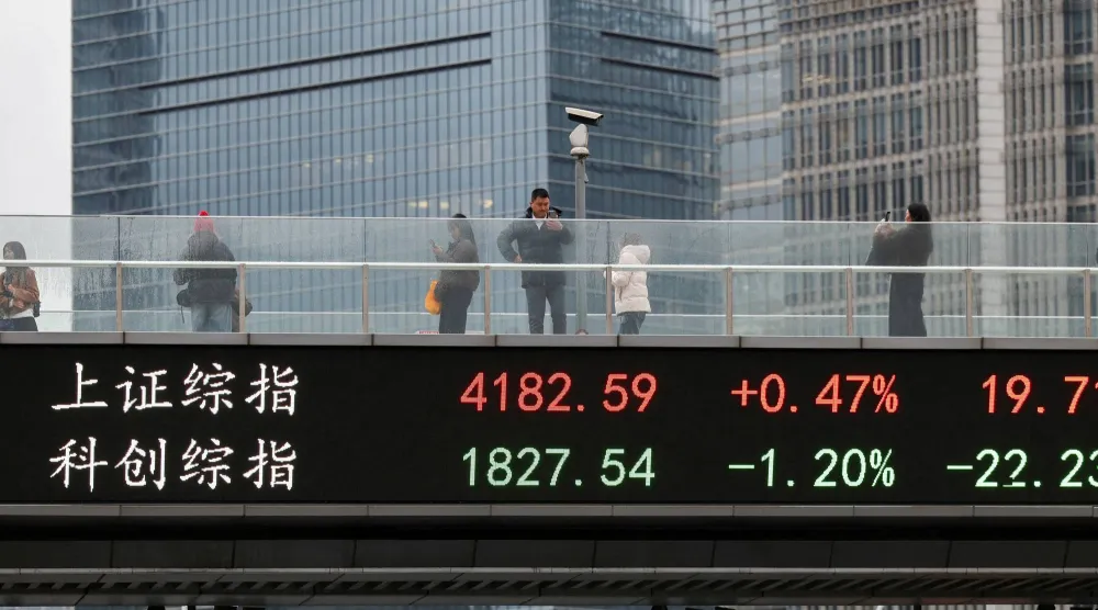 شاشة تعرض حركة الأسهم على جسر بمدينة شنغهاي الصينية (رويترز)