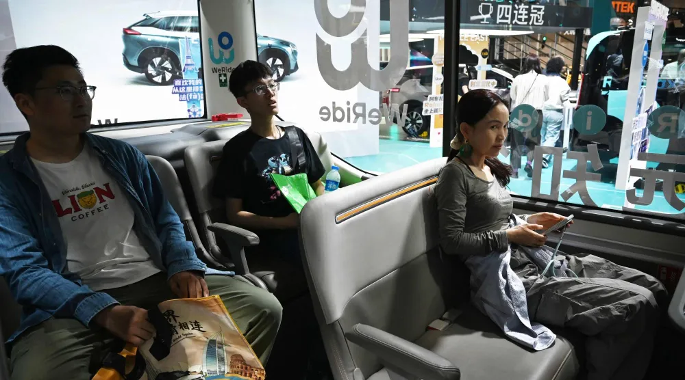 زوار في «معرض سيارات بكين» بالعاصمة الصينية يجربون سيارة ذاتية القيادة (أ.ف.ب)