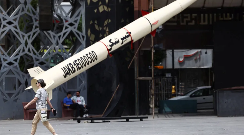 إيرانية تسير بجانب نموذج رمزي لصاروخ «خيبر شكن» الباليستي في طهران اليوم (رويترز)