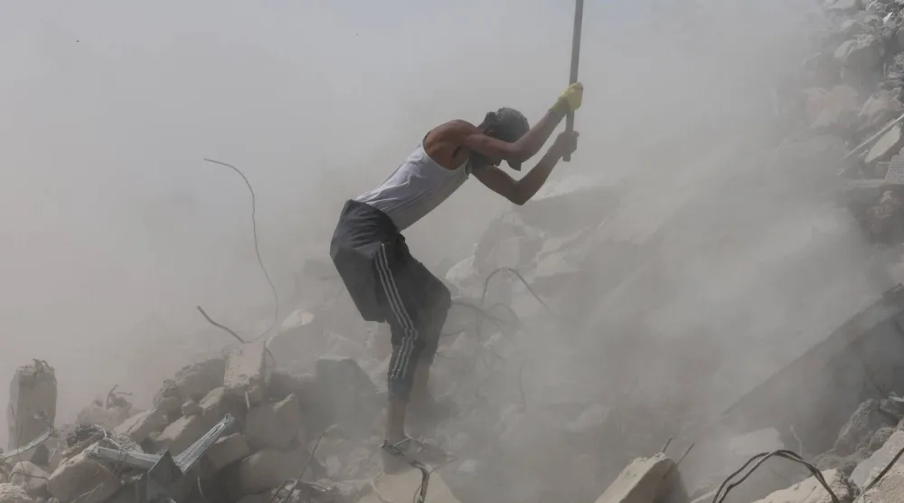 عامل فلسطيني يكسر الخرسانة في أثناء إزالة الأنقاض في خان يونس جنوب قطاع غزة (رويترز)