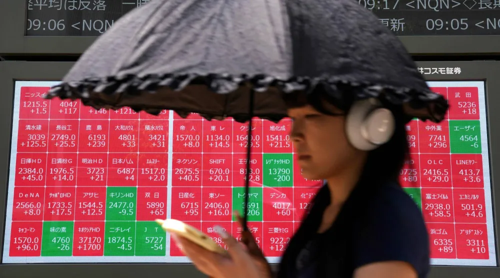امرأة تمر أمام لوحة إلكترونية تعرض أسعار أسهم مؤشر «نيكي» في بورصة طوكيو (أ.ف.ب)