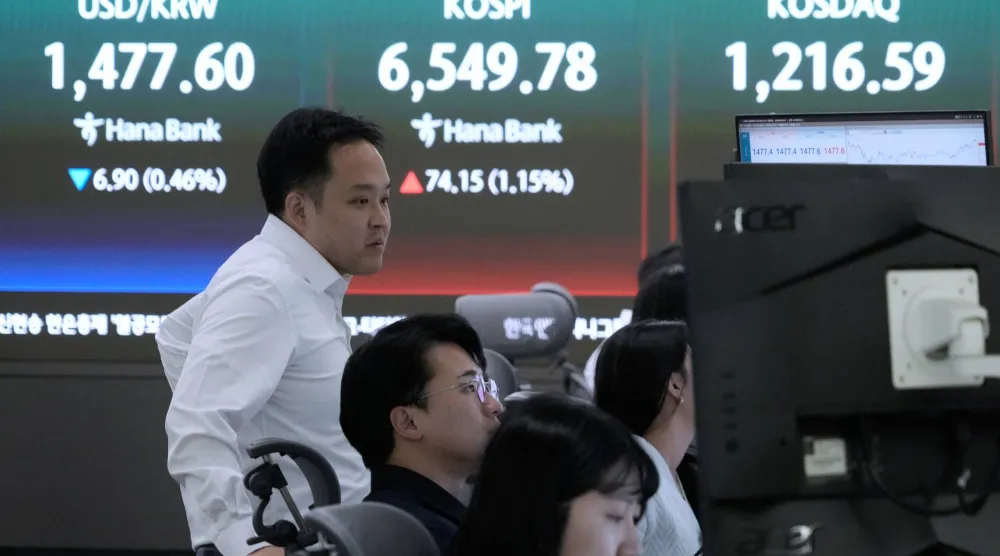 يراقب متداولو العملات شاشات تعرض مؤشر «كوسبي» وسعر صرف الدولار مقابل الوون في بنك هانا بسيول (أ.ب)