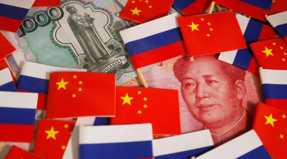 أوراق نقدية من اليوان  والروبل وسط أعلام الصين وروسيا (رويترز)