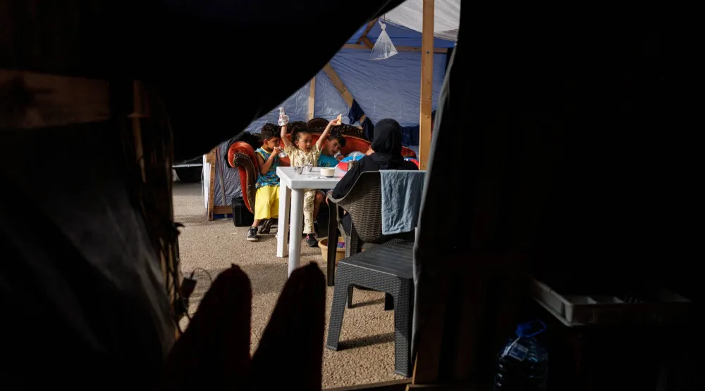أطفال ربيع خريس يتناولون وجبة الإفطار أثناء جلوسهم في مأواهم داخل مخيم مؤقت في بيروت (رويترز)